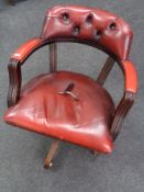 A red buttoned leather swivel captain's armchair