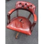 A red buttoned leather swivel captain's armchair