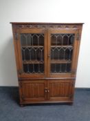 A good quality carved oak double door leaded glass bookcase with linen fold doors beneath