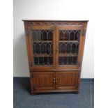 A good quality carved oak double door leaded glass bookcase with linen fold doors beneath