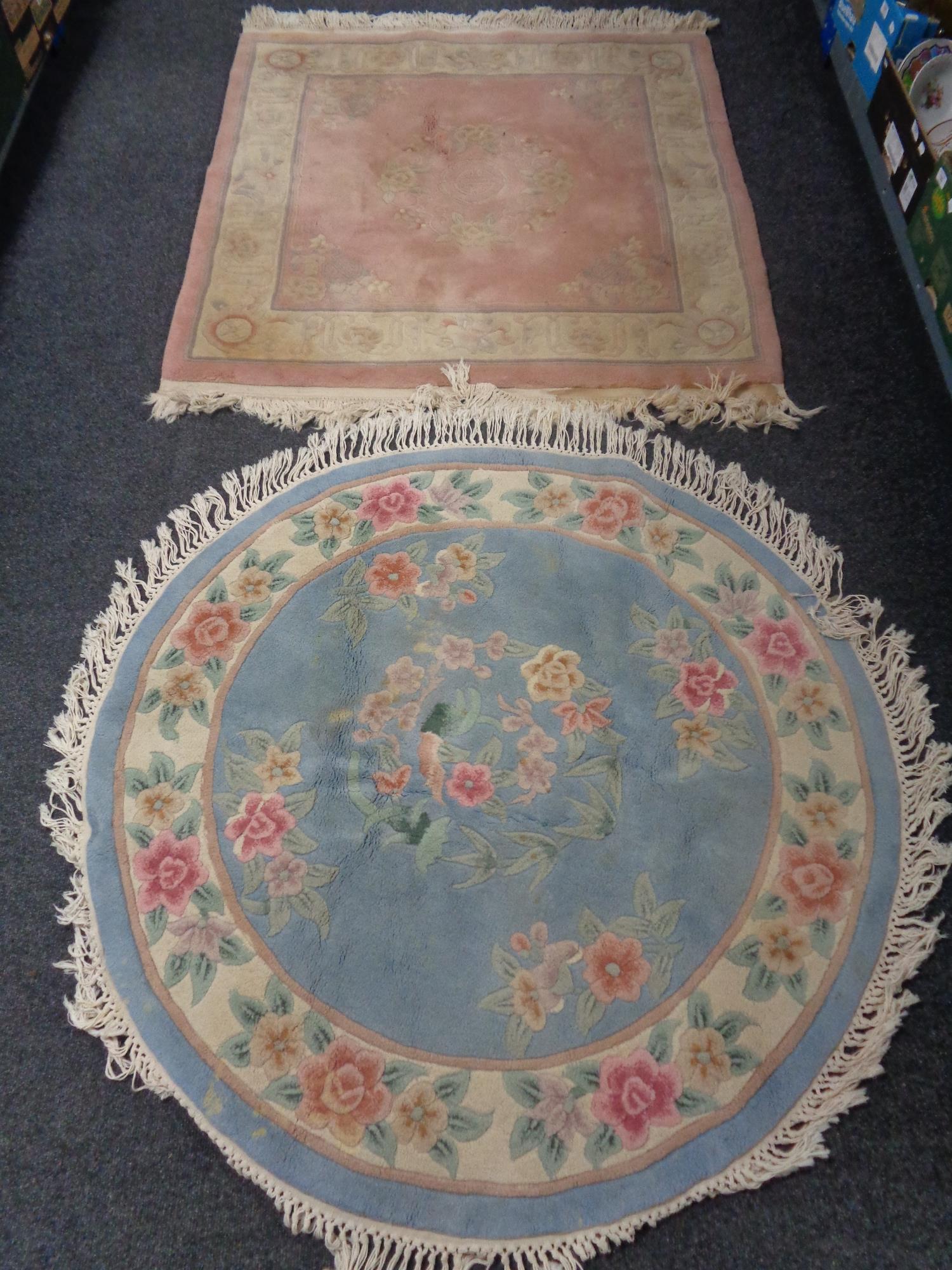 A fringed Chinese floral rug on pink ground together with a further fringed circular Chinese rug on