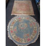 A fringed Chinese floral rug on pink ground together with a further fringed circular Chinese rug on