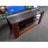 A contemporary wood and black glass three tier TV stand.