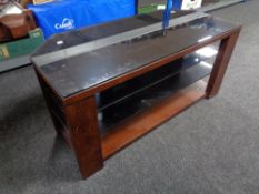 A contemporary wood and black glass three tier TV stand.