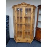 A shaped pine double door display cabinet fitted drawer beneath