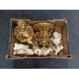 A box containing a gilt painted chalk cherub wall shelf together with four further cherub figures.