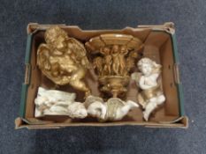 A box containing a gilt painted chalk cherub wall shelf together with four further cherub figures.