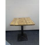 A pine square topped cafe table on Art Deco style metal pedestal