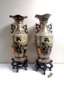 A pair of Japanese twin handled vases depicting geisha, on stands,