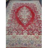 A large fringed floral carpet on red ground