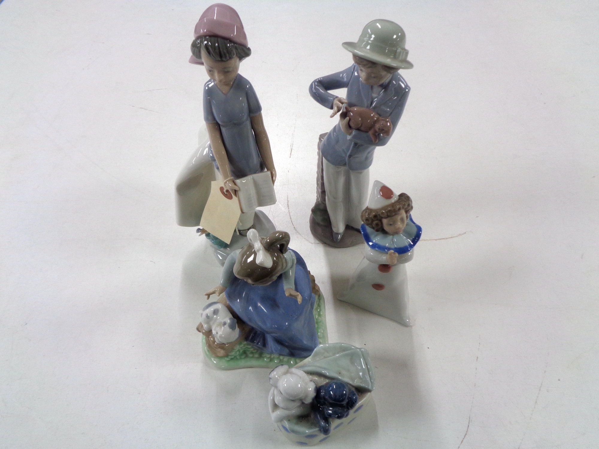 Five Nao figures to include girl with book, girl with puppy, puppies in basket, clown,