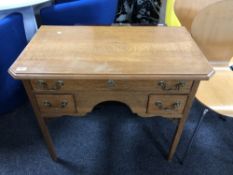 A oak three drawer lowboy with brass drop handles