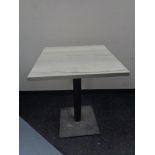 A square topped cafe table on metal pedestal