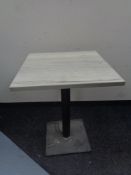 A square topped cafe table on metal pedestal