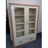 A good quality contemporary wood framed display cabinet with cream high gloss double doors,