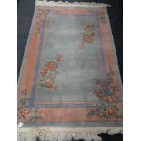 A fringed Chinese floral rug on pink and blue ground.
