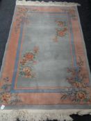 A fringed Chinese floral rug on pink and blue ground.