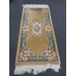 A fringed Chinese floral rug on gold ground