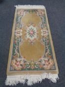 A fringed Chinese floral rug on gold ground