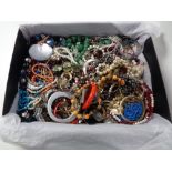 A box containing a quantity of costume jewellery to include beaded necklaces, bangles, brooches,