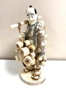 A Japanese carved bone and penwork okimono, travelling basket seller,