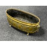A brass embossed oval planter on paw feet,