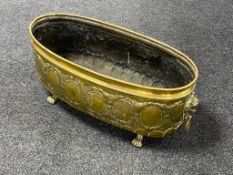 A brass embossed oval planter on paw feet,