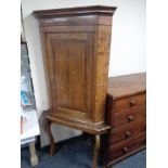 A George III oak corner cabinet on later stand