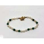 A pearl and malachite necklace with gold spaces and clasp.