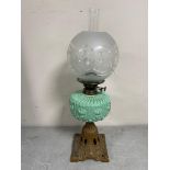 A 19th century oil lamp on cast iron base with green glass reservoir,