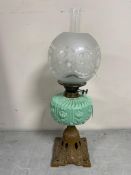 A 19th century oil lamp on cast iron base with green glass reservoir,