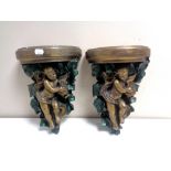 A pair of painted chalk cherub wall shelves.