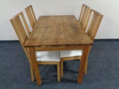 A contemporary pine kitchen table together with a set of four rail backed chairs