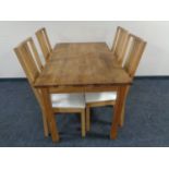 A contemporary pine kitchen table together with a set of four rail backed chairs