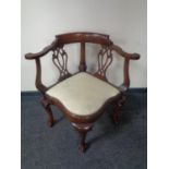 A reproduction mahogany corner armchair on claw and ball feet.