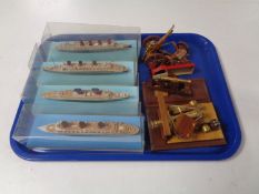 A tray containing miniature wooden cannons and four miniature models of cruise liners in display