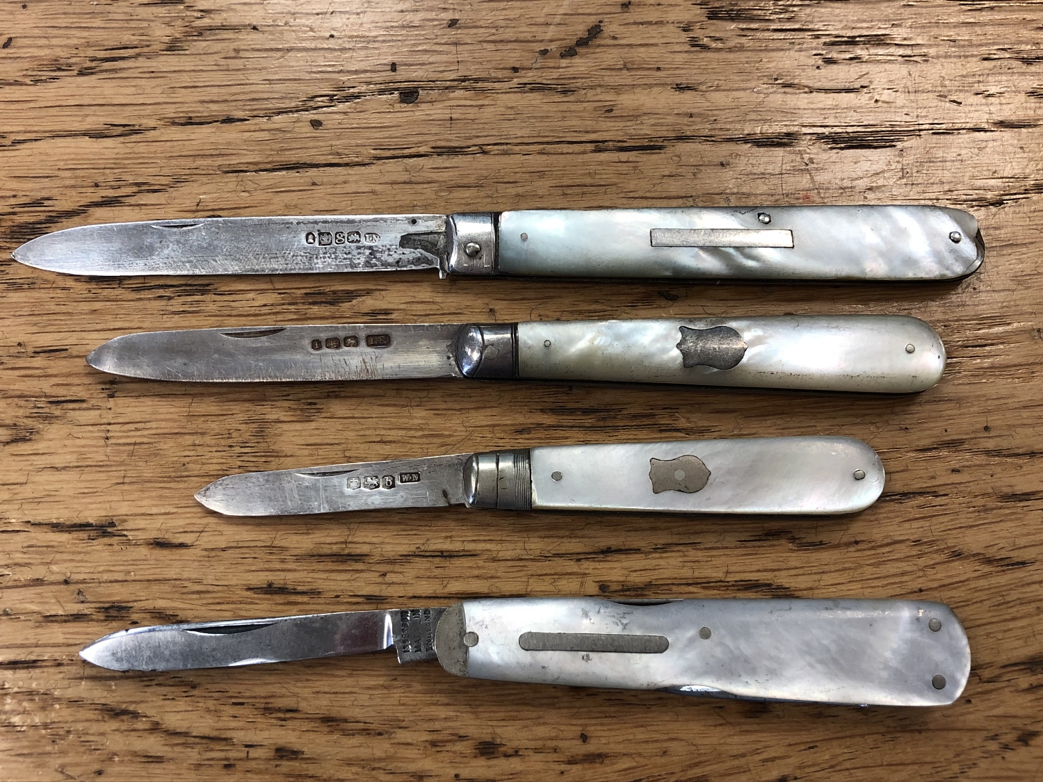 Three antique silver and mother of pearl handled fruit knives, plus one with stainless steel blade.