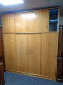 A 20th century teak four door sliding wardrobe fitted cupboards above