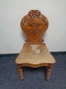 An antique carved oak hall chair on turned legs