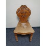 An antique carved oak hall chair on turned legs