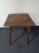 A carved Edwardian oak occasional table on tapered legs.