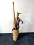 A wicker stick pot containing a collection of various walking sticks, umbrellas,