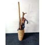 A wicker stick pot containing a collection of various walking sticks, umbrellas,