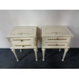 A pair of painted cream and gilt two drawer bedside chests on reeded legs.