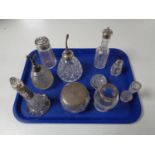 A tray containing a quantity of silver lidded and rimmed dressing table bottles,