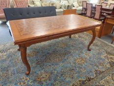 A contemporary inlaid extending dining table on cabriole legs in a mahogany and walnut finish.