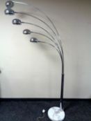 A contemporary chrome five way adjustable floor lamp on a circular marble base.