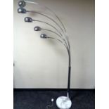 A contemporary chrome five way adjustable floor lamp on a circular marble base.