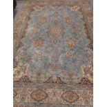 A fringed woolen machine made carpet of Persian design on blue ground, 365cm by 254cm.