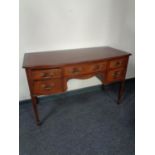 A 20th century inlaid mahogany bow fronted writing desk on raised legs, fitted five drawers.